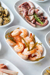 Set of Seafood Dishes. Seafood on a plate. On a white wooden background. Selective focus Shrimp. Prawns, lakerda, octopus salad, mussels with marinade
