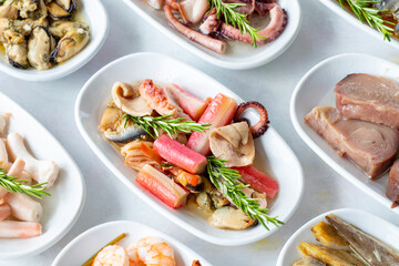 Set of Seafood Dishes. Seafood on a plate. On a white wooden background. Selective focus fish salad. Shrimp, lakerda, octopus salad, mussels with marinade, fish salad