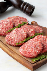 Raw beef burger patties on wooden background.
