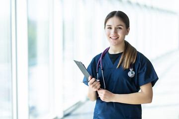 Smiling young female doctor holding a clipboard, healthcare concept