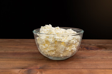 Cottage cheese in glass bowl on a dark background