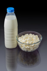 Cottage cheese in bowl, milk bottle on dark reflective surface