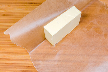 Piece of butter on waxed paper on a wooden surface