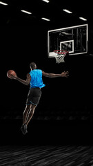 One young sportsman basketball player training in gym, idoors isolated on dark background. Concept...