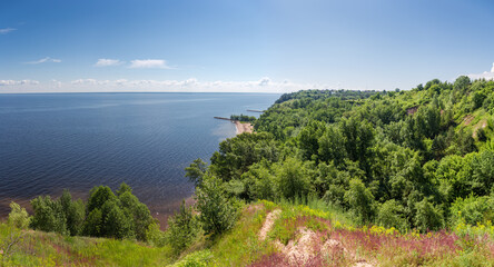 Steep hilly shore of big reservoir overgrown with forest