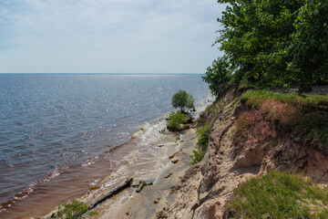 Steep sandy shore of big reservoir overgrown with forest