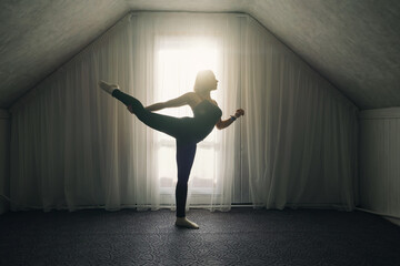 Woman doing yoga stretching exercises near big window at home