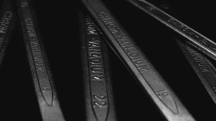 Fototapeta premium Wrenches, chrom vanadium spanners on black, dark background, steel hand work tools closeup, abstract wallpaper. Selective focus