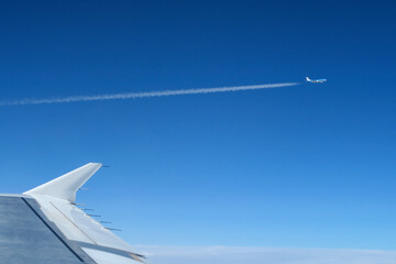 Samolot pasażerski na tle nieba widziany z okna innego samolotu - obrazy, fototapety, plakaty