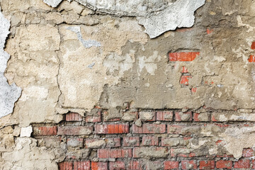 A fragment of an old brick wall covered with a layer of destroyed plaster. As a natural stone background and texture.