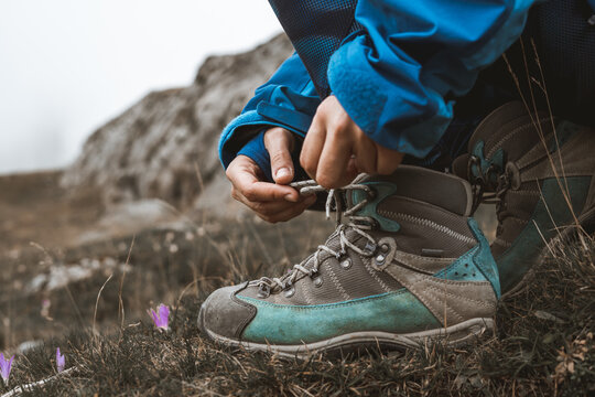Traveler tying shoelaces on boot in mountains