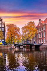 Fototapeta premium Amsterdam, Netherlands. Panoramic view of autumn Dutch city. Famous channel of Amstel river. Evening cityscape. Colorful sunset scene of famous travel destination in Europe. Romantic traveling place.