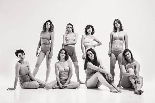 Women without makeup in beige clothes. Black and white photo with a group of girls on a light background. Girls with natural beauty. A group of women in one photo are standing in their underwear
