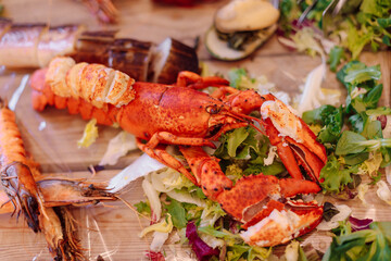 Festively decorated baked crab lies onwooden platter surrounded by other seafood . Lunch at the restaurant. Travel and recreation. Fish buffet. Fish menu. Fish restaurant.