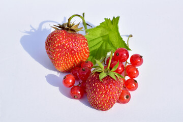 Healthy food, ripe berries. Strawberries and red currants on a white table.