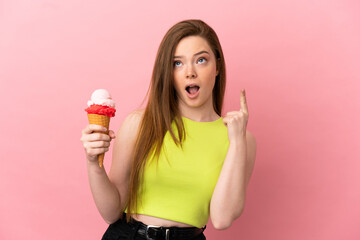 Teenager girl with a cornet ice cream over isolated pink background thinking an idea pointing the finger up