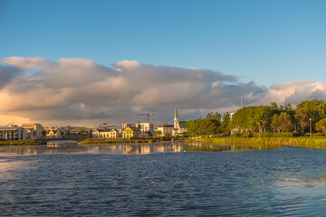 Obraz premium Beautiful view over historical downtown in Reykjavik at warm Summer sunset in the city lake Tjornin, and city park, Iceland.
