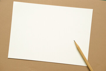 top view of wooden pencil placed on  blank white a4 paper brochure mock up card on brown background.