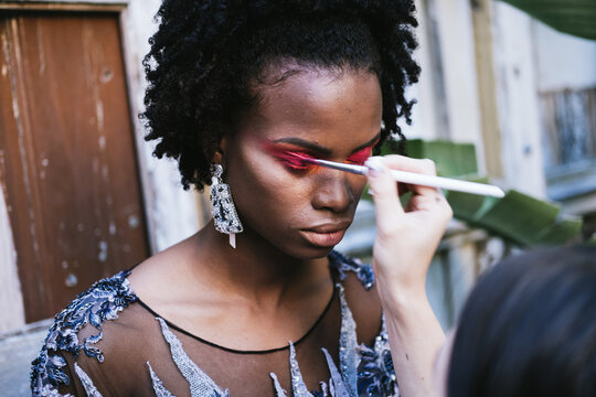 Make up artist doing makeup for african fashion model outdoors