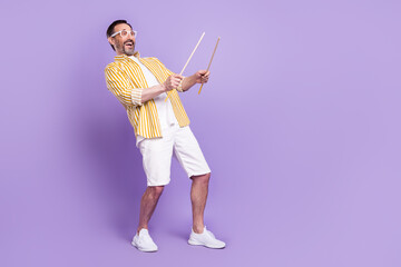 Photo of sweet funny mature man dressed striped shirt spectacles playing drums empty space smiling isolated violet color background
