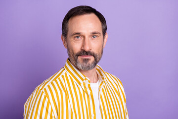 Photo of mature handsome man good mood smile wear yellow striped shirt isolated on purple color background