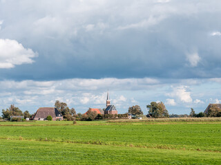 Polder with grassland, farmhouse and church of Cornjum, Friesland, Netherlands