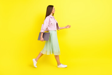 Full body profile photo of nice brunette hairdo young lady go with laptop wear spectacles pink shirt skirt isolated on yellow color background