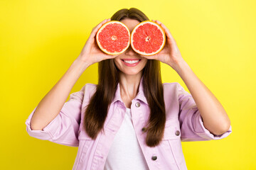 Photo portrait young woman covering eyes with two grapefruit halfs playful isolated vibrant yellow color background