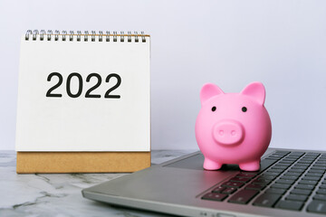 Piggy Bank on top of laptop and year 2022 calendar