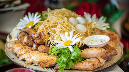 Chicken pieces, chicken legs with French fries, garnished with lettuce and chamomile flowers.