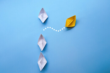 yellow paper ship moves differently with with white paper ship.leadership and business concept.