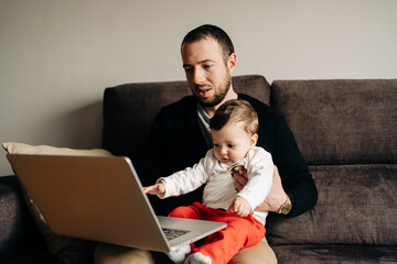 Young father with little son watching video on netbook