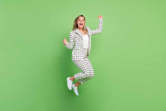 Full length body size view of attractive cheerful lucky girl jumping having fun isolated over bright green color background