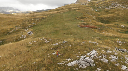 Aerial view of a lonely young tourist tracker walking along the hills
