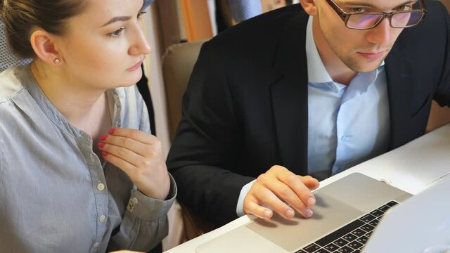 Group of young colleagues comparing sales result graph on paper with chart on computer screen at office. Professional coworkers analyzing financial reports during business meeting indoor. Close up