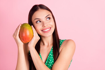 Photo portrait brunette smiling keeping juicy mango fruit looking empty space isolated pastel pink...