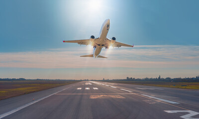 Fototapeta na wymiar White Passenger plane fly up over take-off runway from airport