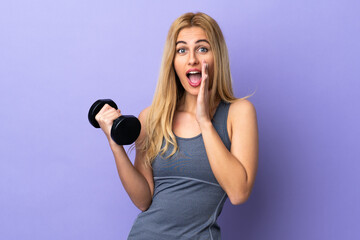 Young blonde sport woman making weightlifting over isolated purple background shouting with mouth wide open