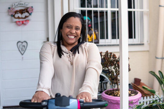 Portrait Of Happy Disabled Woman In Electric Wheelchair Smiling At Camera.