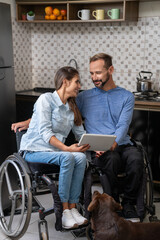 lovely disabled couple looking at each other holding tablet.