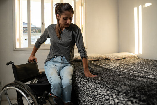 young woman transferring to bed from wheelchair.