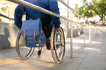 person in wheelchair with blue backpack arriving destination.