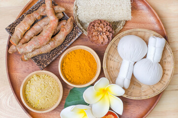 Organic turmeric and thanaka powder with herbal massage compress, aroma candle and spa equipment on wooden background, for health care and spa treatment concept