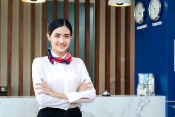 Portrait of smiling young beautiful Asian female receptionist confidential standing with arms...