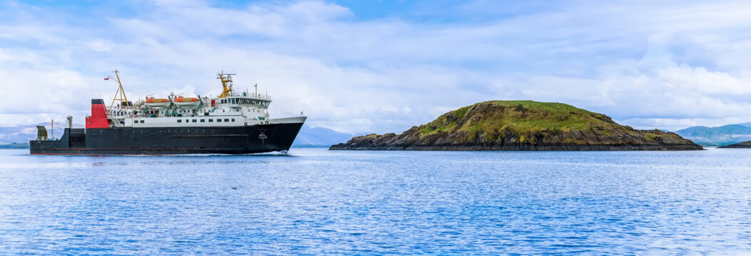 A Ferry Boat Passes Maiden Island In Firth Of Lorn Near To Oban, Scotland On A Summers Day