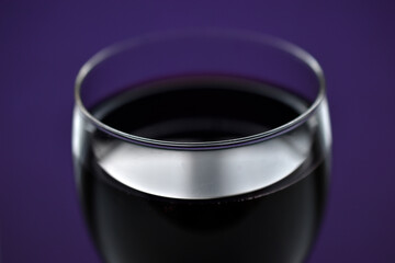 A large glass of red wine on a purple background