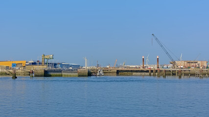 Fototapeta premium Dock in the industrial harbour of of Boulogne sur mer, Oise, France, with windmills, crane and hangars 