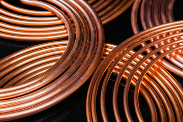 Twisted new copper tubes on a black background.