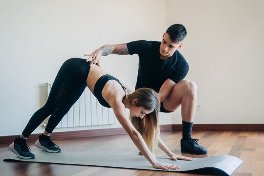 Trainer helping woman with exercise - Powered by Adobe