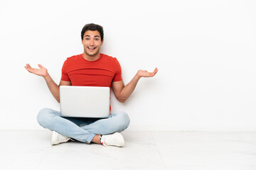 Caucasian handsome man with a laptop sitting on the floor with shocked facial expression